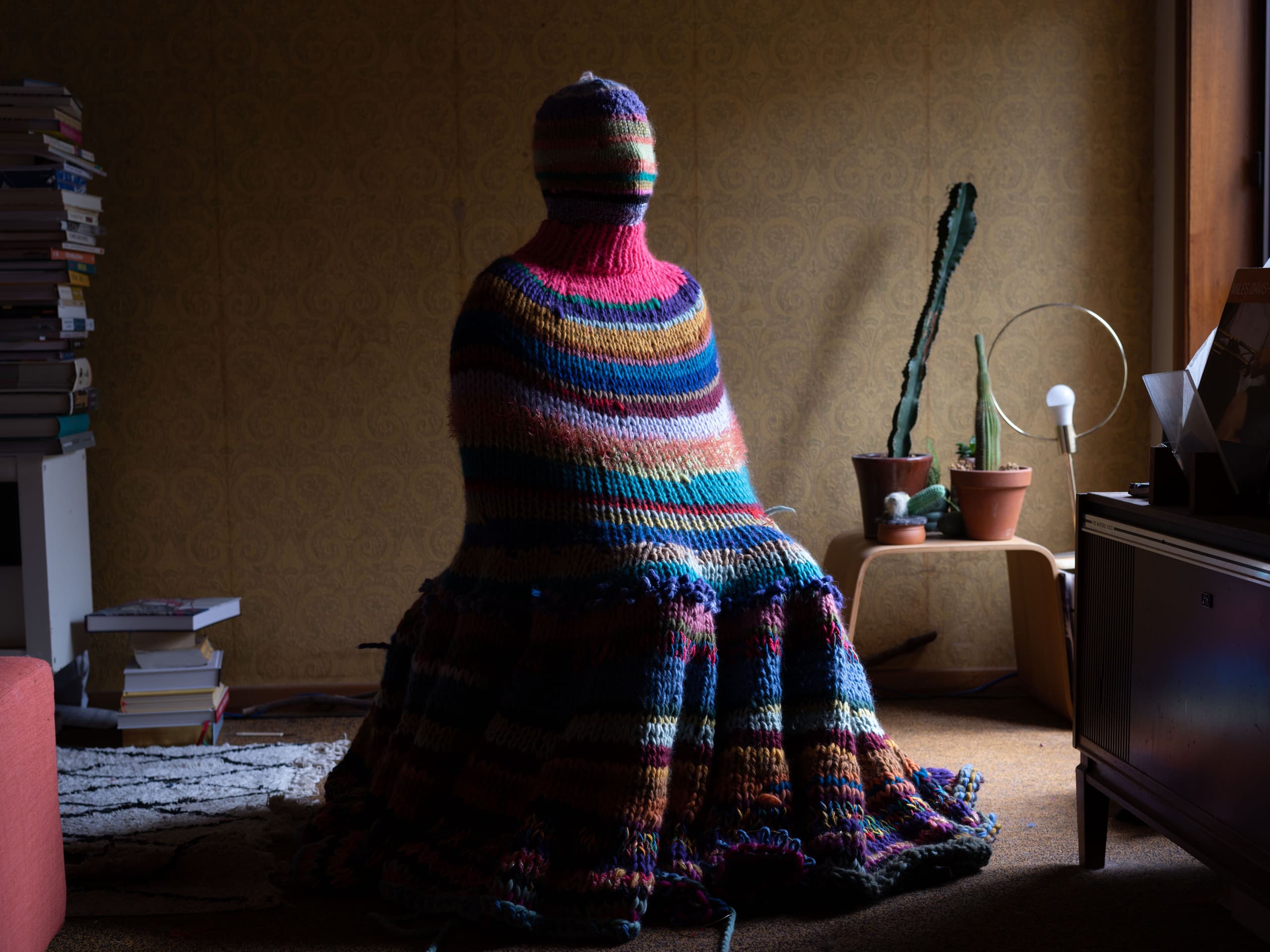 a person sitting on a chair covered with a crochet blanket
