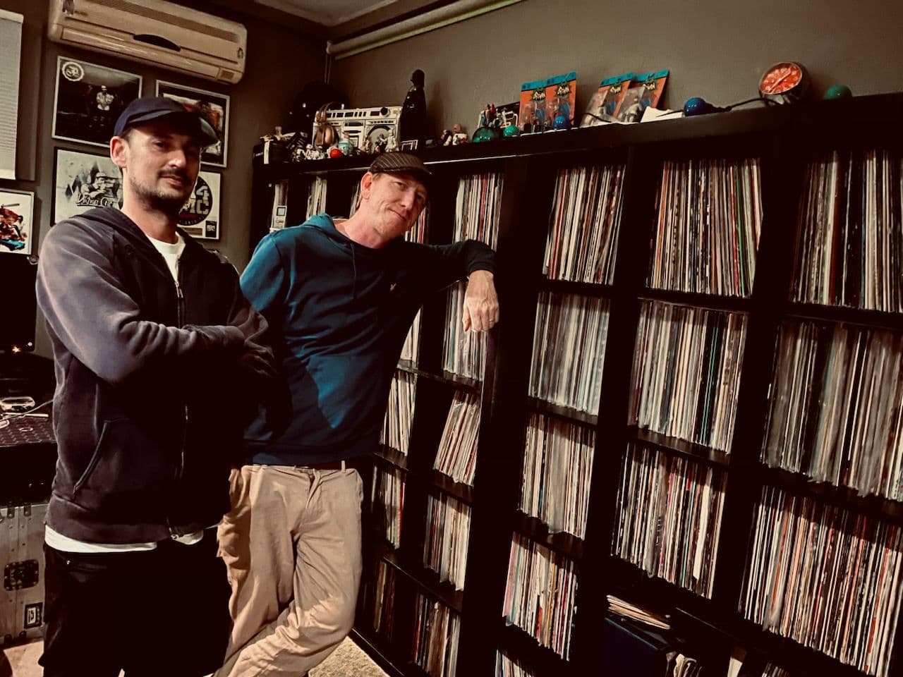 Two men standing in front of an extensive vinyl record collection