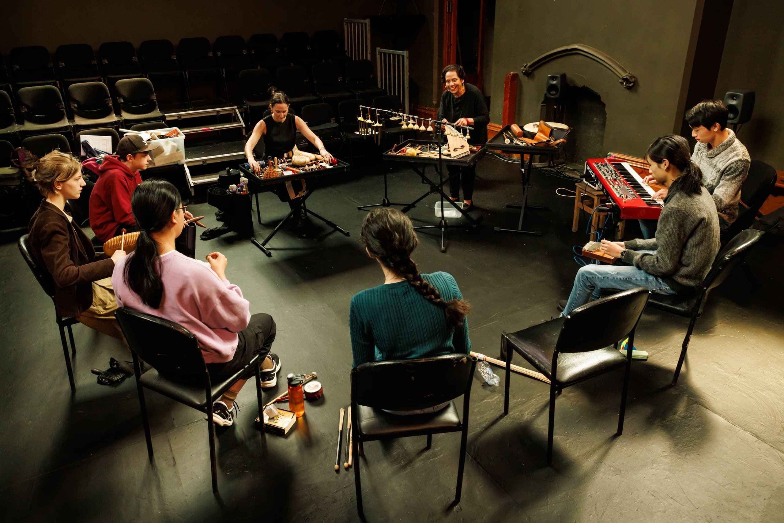 Friends sitting together at a table, surrounded by musical instruments and food, sharing music and laughter in a cozy setting.