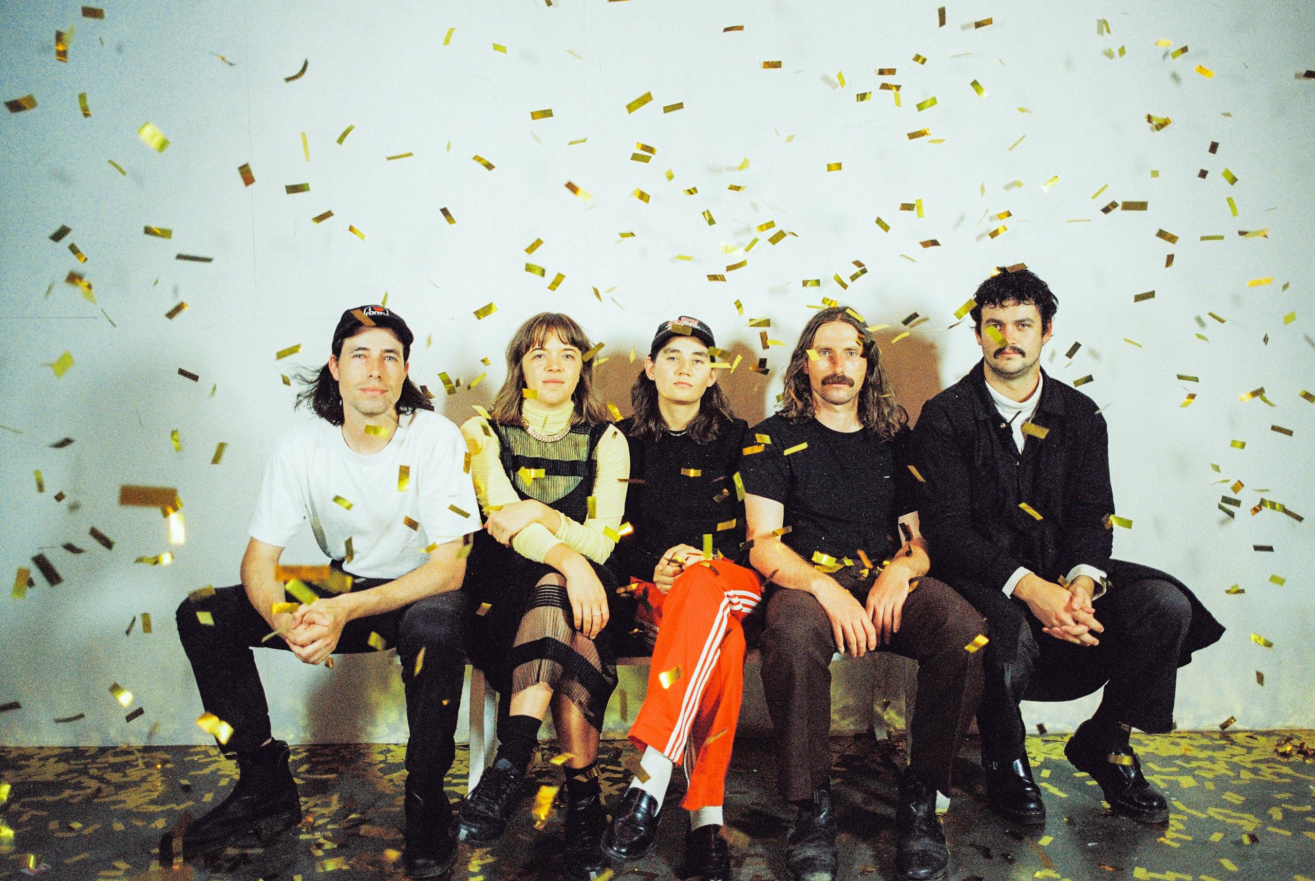A band sitting with gold confetti raining down
