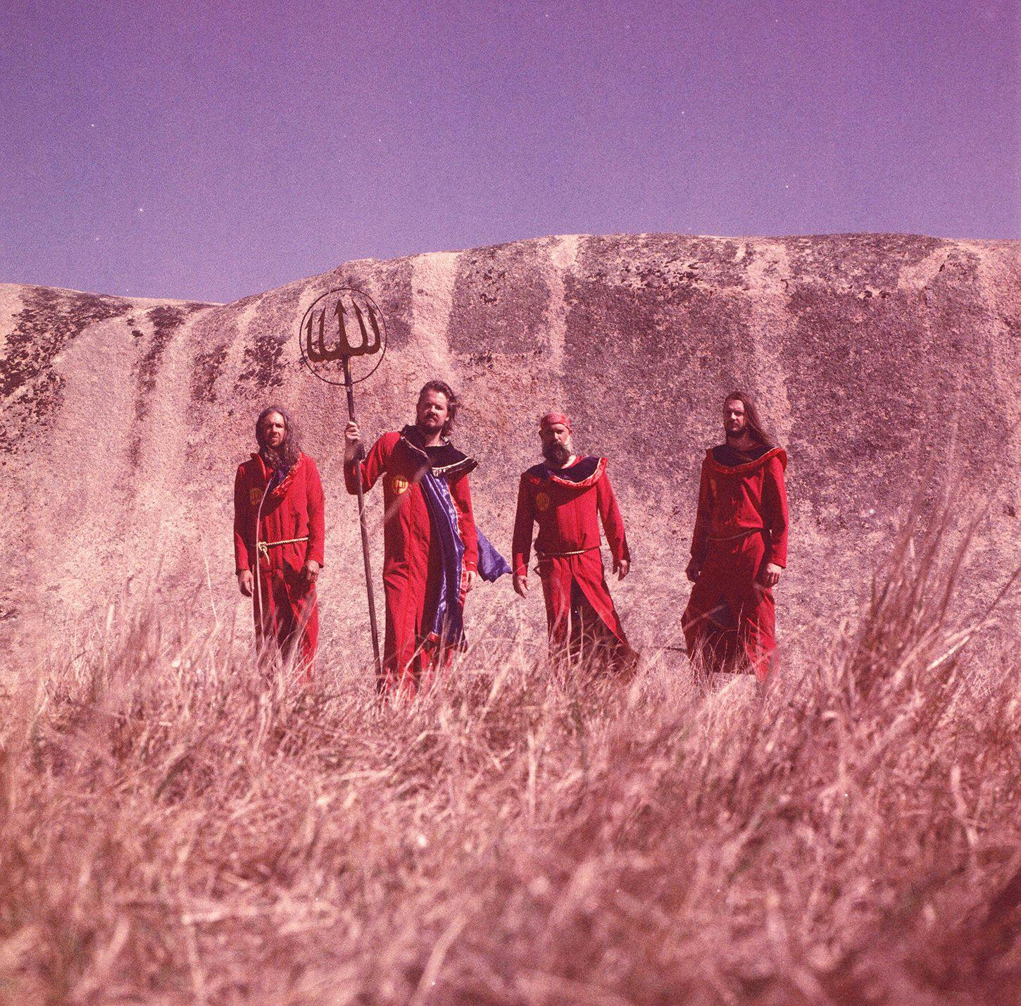 A group of men in red robes standing in a field.