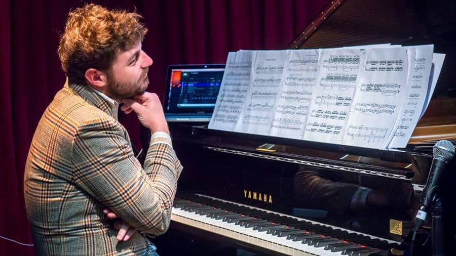 A man sitting at a piano looking at sheet music