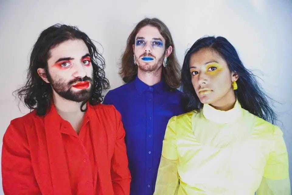 Three people with painted faces standing together, expressing their unique personalities through vibrant colors.