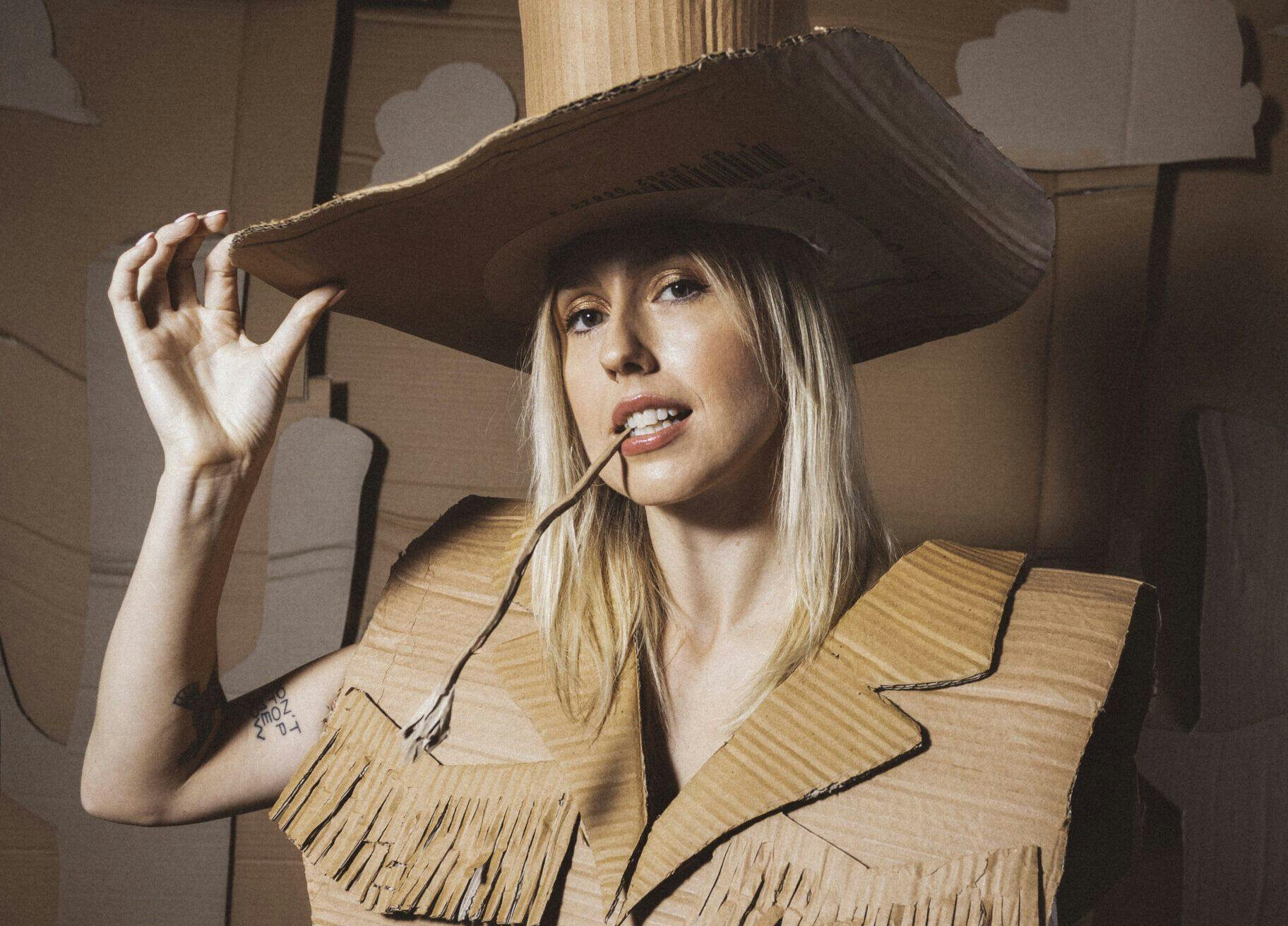 A woman wearing a cardboard costume and hat, looking creative and playful.