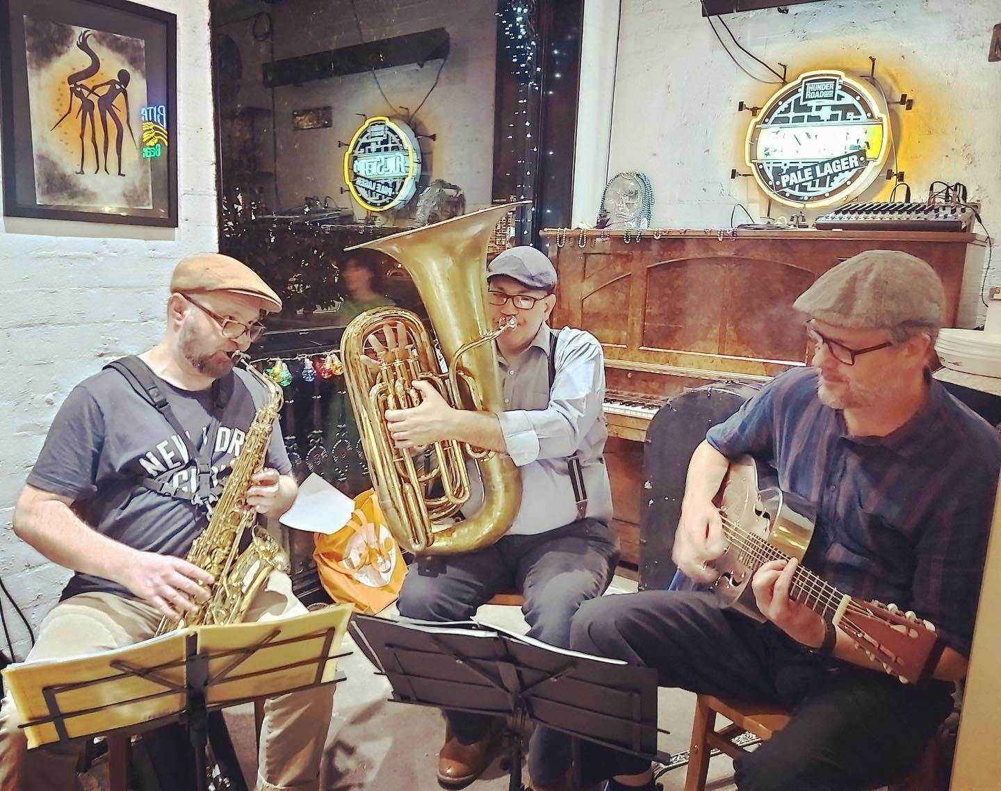 Three men playing music in a room with a bar.