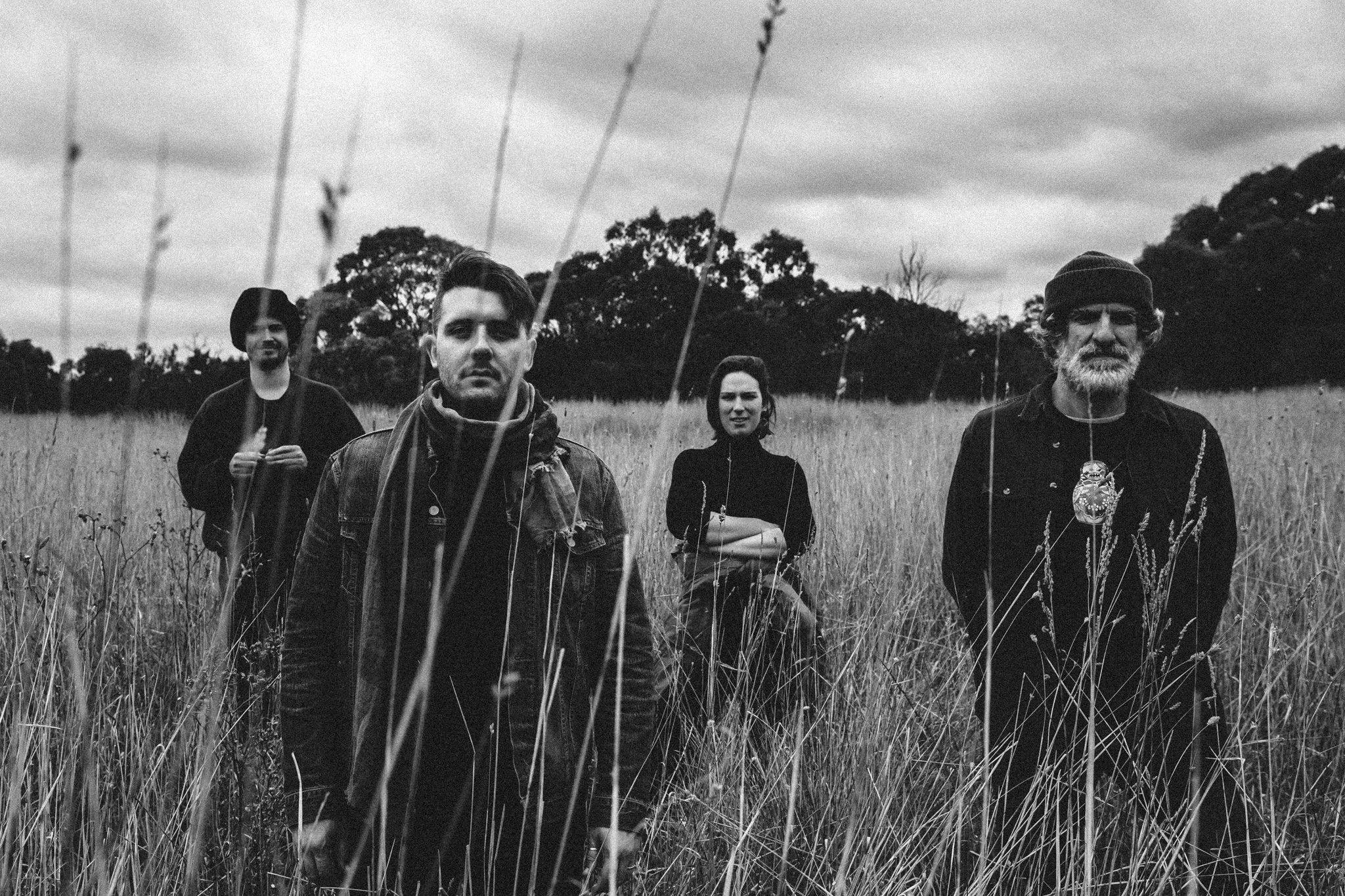 black and white photo of band standing in long grass